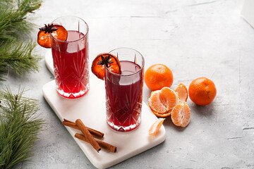 Traditional christmas beverage mulled wine with red cherry juice, orange tangerines, cinnamon sticks and anise on a marble board