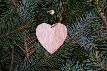Christmas toy, a wooden heart, on the branches of a Christmas tree, photo indoors with light