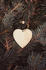 Christmas toy, a wooden heart, on the branches of a Christmas tree, photo indoors with light