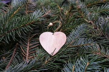 Christmas toy, a wooden heart, on the branches of a Christmas tree, photo indoors with light