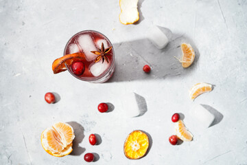 Traditional christmas beverage mulled wine with red cherry juice, orange tangerines, cinnamon sticks, ice cubes and anise, top view