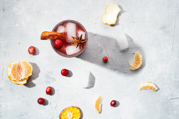 Traditional christmas beverage mulled wine with red cherry juice, orange tangerines, cinnamon sticks, ice cubes and anise, top view