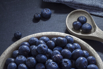 blueberries in spoon and wooden bowl, on slate table. Overhead view	