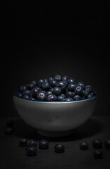 Blueberry dark meal. White bowl and ceramine zaul filled with blueberries with slight overhead lighting