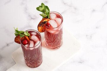 Traditional christmas beverage mulled wine with red cherry juice, orange tangerines, cinnamon sticks, ice cubes and anise on marble board