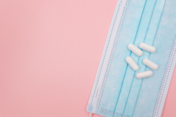 White Pills or Tablets on Medical Face Mask, Lying on Pink Background. Pharmaceutical Industry and...
