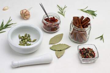 Cinnamon sticks in jar. Cardamom in mortar and pestle on table.