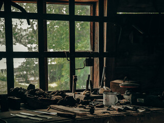 Forge, tools for a blacksmith, blacksmith's work table, old workplace, window in a hut, summer