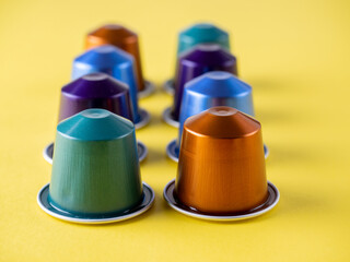 many aluminum coffee capsules are displayed in a row on a yellow background. Food pattern. Capsules for the coffee machine