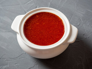 Close-up of soup borscht in a white ceramic soup bowl on a gray textured background. Traditional soup for Russia and Ukraine.