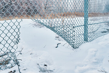 Hole in wire border fence. Illegal trespassing. Escape from prison or closed institution for mentally ill. Maximum security detention facility. Winter snowy weather.