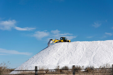 Excavator working in a huge pile salt at saltworks