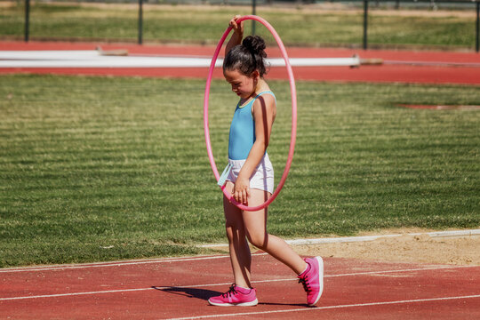 Niña con el aro hula hula como parte de su entrenamiento de atletismo en las instalaciones deportivas.