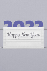 New Year's postcard with paper figurines 2022 under a face mask with the inscription Happy New Year.
