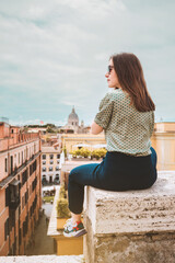 Fototapeta na wymiar Girl back, young woman with sunglasses and brown hair от the roof top with beautiful view, Rome, Italy. Vacation in Italy, Europe. Back of a beautiful lady.