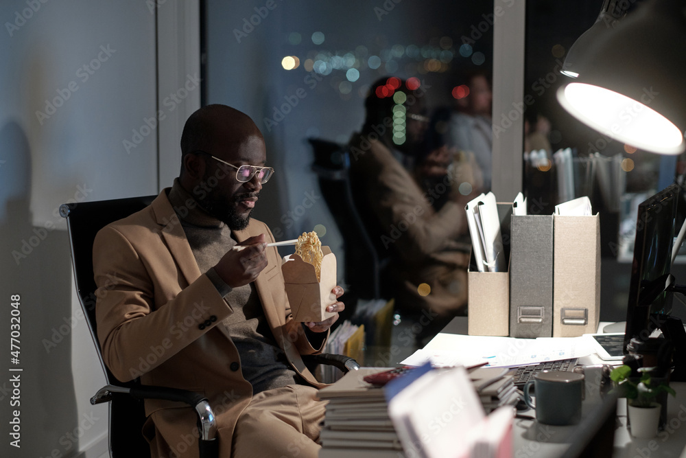 Aufkleber hungry young businessman with chopsticks and box of chinese wok sitting by workplace in front of com