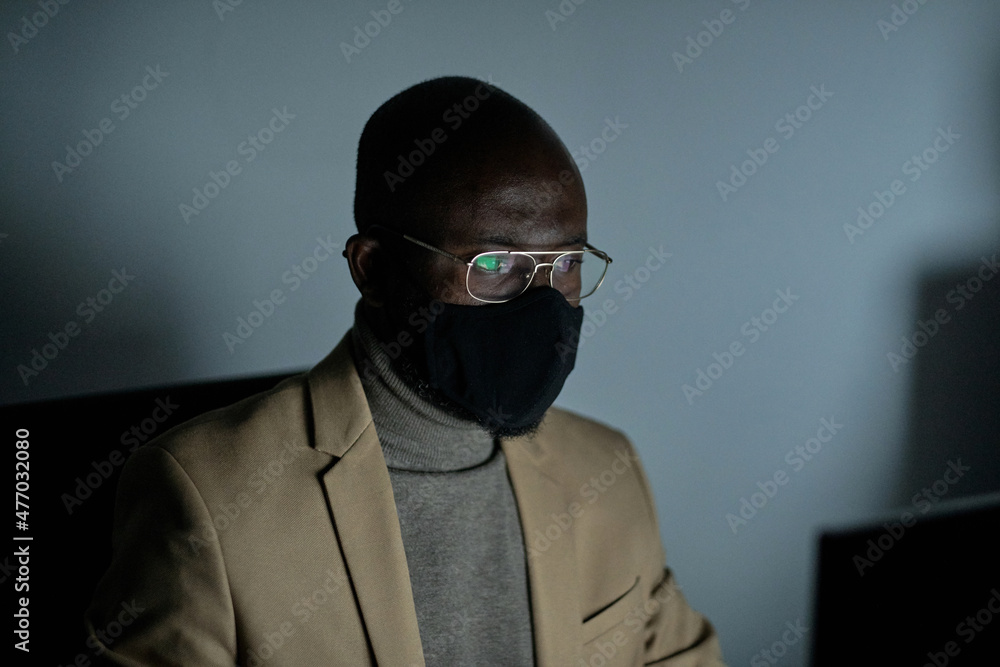 Aufkleber young african businessman in protective mask and eyeglasses sitting in front of computer in office a