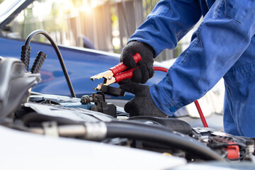 Close up of hand mechanic car service battery with electricity through jumper cables. Service work by professional technicians concept.