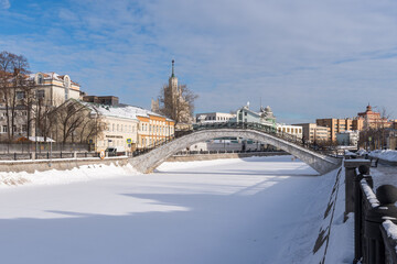 Pedestrian Sadovnichesky Bridge across the Vodootvodny Canal on a clear winter day. In the distance is a skyscraper on the Kotelnicheskaya embankment.  Moscow
