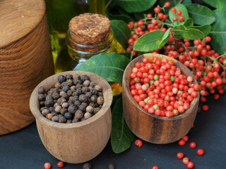 Spices and condiments, black allspice, pink brazilian pepper, olive oil on black vintage background
