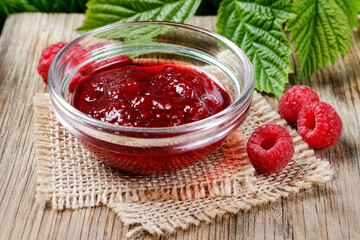 Bowl of raspberry jam on a wooden table.