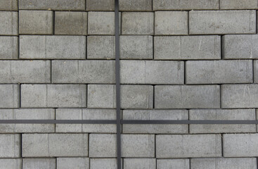 Concrete road tiles for the construction of a parking lot are stacked on top of each other in even rows.