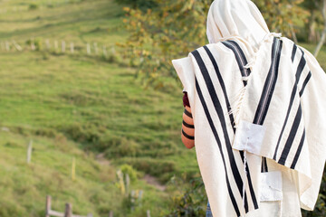 Jew wearing tallit and Tefillin or Phylactery praying outdoors against a background of nature. Jew...