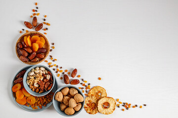 Mixed nuts and dried fruits on a plate on a white wooden table with copy space.