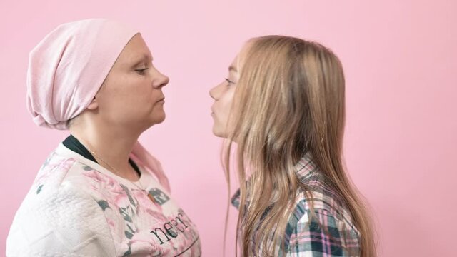 A woman with cancer is kissing her daughter.