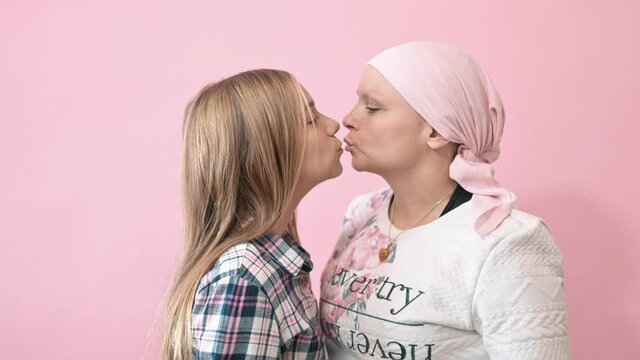 A woman with cancer is kissing her daughter.