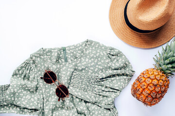 Summer casual style. Stylish woman clothes and accessories. Dress, sunglasses, hat and pineapple on white background. Flat lay, top view - obrazy, fototapety, plakaty