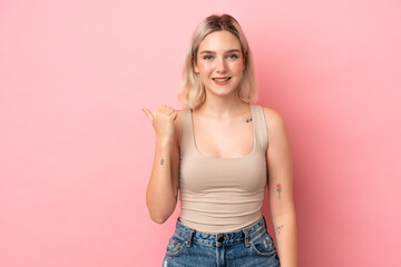 Young caucasian woman isolated on pink background pointing to the side to present a product
