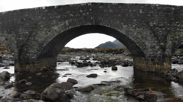 Aerial footage from the centre of the Isle of Skye near it's Sligachan Old Bridge, close to Portree and the Scottish Highlands captures the vast plains between the Cullin Mountain Range.