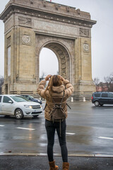 Rear View Of A Female Tourist Taking A Picture At The Triumphal Arch Monument In Bucharest,...