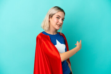 Super Hero caucasian woman isolated on blue background pointing back