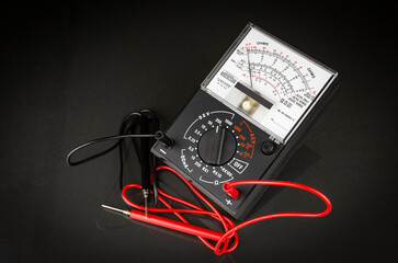 an analog multimeter with test leads - voltmeter, ammeter and ohmmeter isolated on a black...