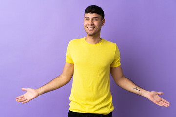 Young Colombian man isolated on purple background happy and smiling