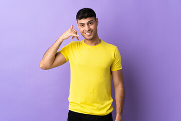 Young Colombian man isolated on purple background making phone gesture. Call me back sign