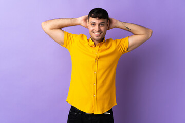 Young Colombian man isolated on purple background laughing