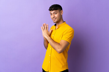 Young Colombian man isolated on purple background scheming something