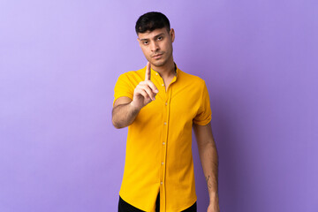 Young Colombian man isolated on purple background counting one with serious expression
