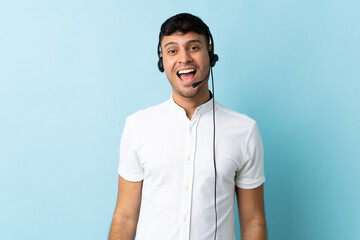 Telemarketer Colombian man working with a headset over isolated background with surprise facial expression