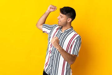 Young Colombian man isolated on yellow background celebrating a victory