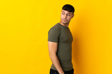 Young Colombian man isolated on yellow background . Portrait