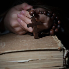 Close up hands with wooden rosary. Selective focus.