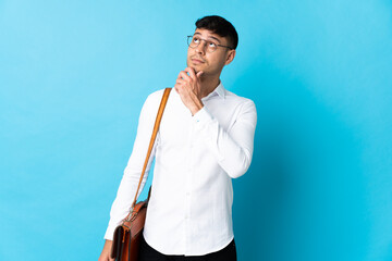 Young business Colombian man isolated on blue background and looking up