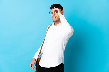 Young business Colombian man isolated on blue background doing surprise gesture while looking to the side