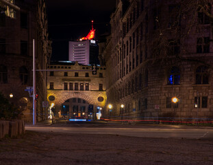 Fototapeta premium Historischer Beamten-Übergang am Neuen Rathaus Leipzig bei Nacht, beleuchtete Architektur mit City-Hochhaus im Hintergrund, Leipzig, Sachsen, Deutschland