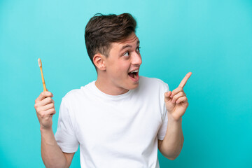 Young Brazilian man brushing teeth isolated on blue background intending to realizes the solution while lifting a finger up