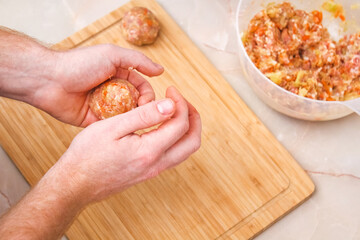 A man sculpts lazy cabbage rolls from minced meat, cabbage, rice. The man is forming meat balls.
